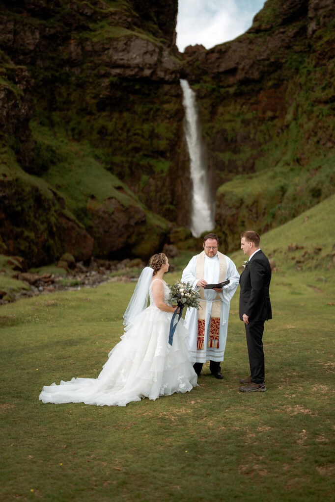 priest marries bride and groom in front of waterfall during iceland elopement.