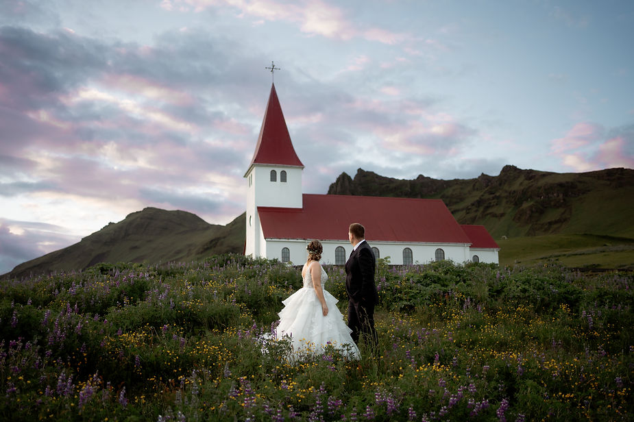 Bride and groom stand in front of church and watch the sunset during iceland adventure wedding photos.