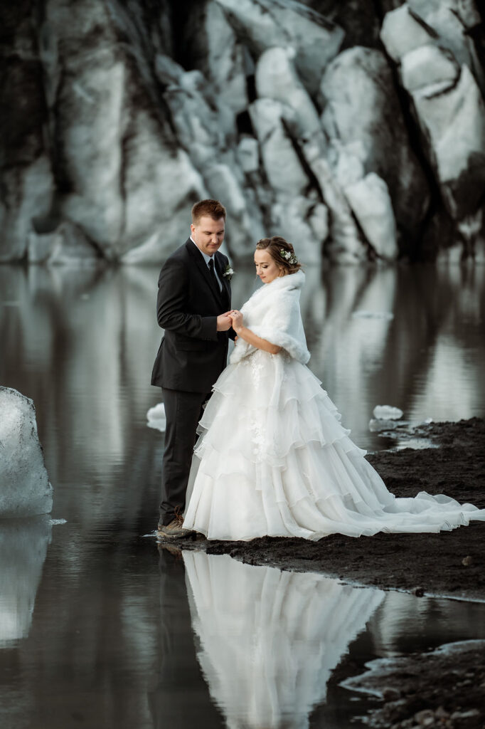 bride and groom stand in front of glacier during iceland wedding photos.