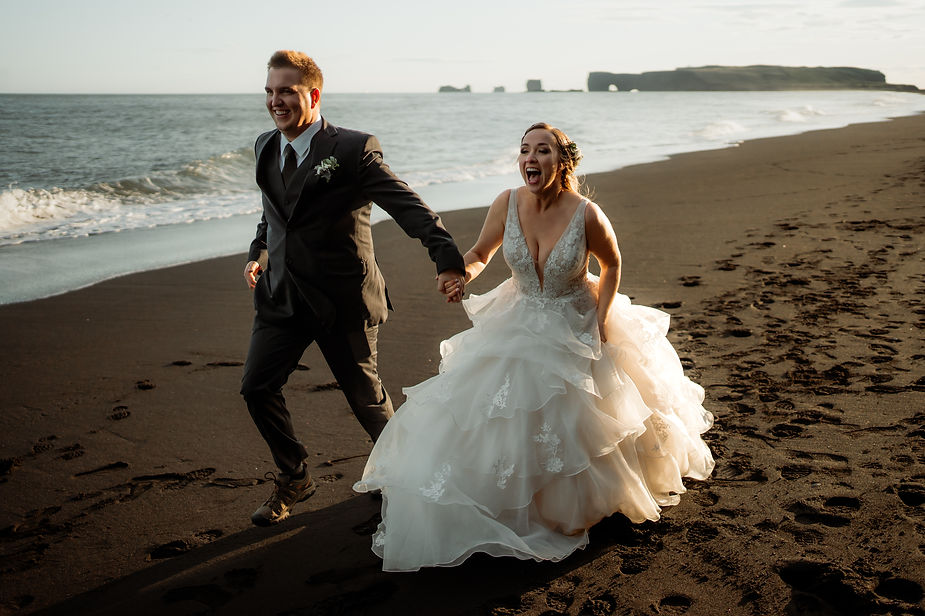 Bride and groom run along beach during iceland elopement photos.