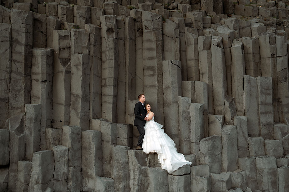 bride and groom stand on rock formation during iceland wedding portraits.