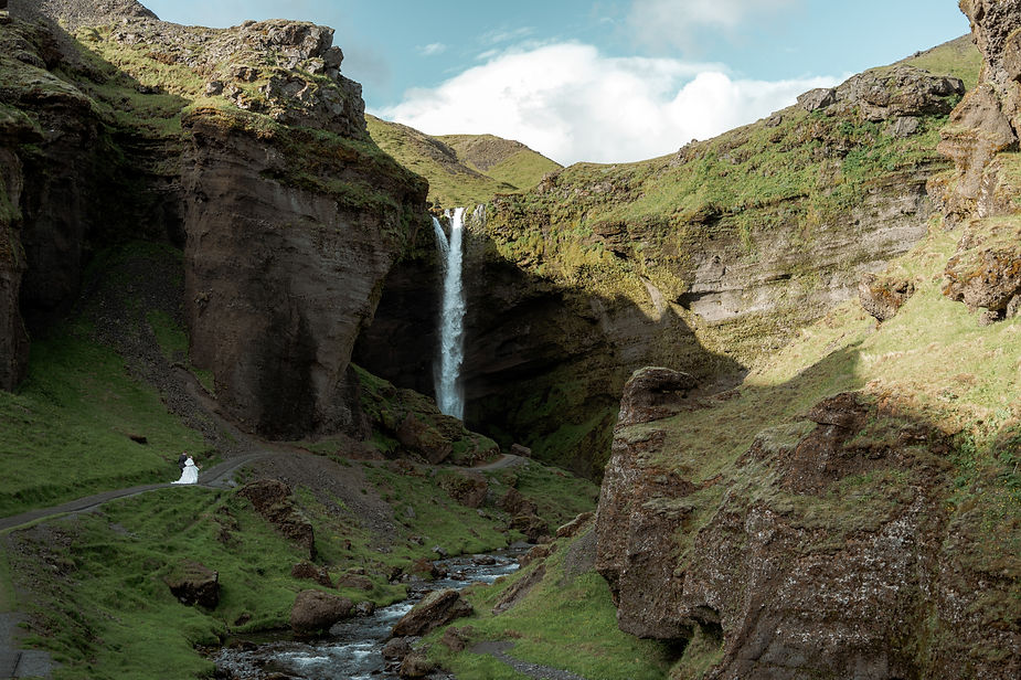 bride and groom hike towrds waterfall during adventure iceland elopement.