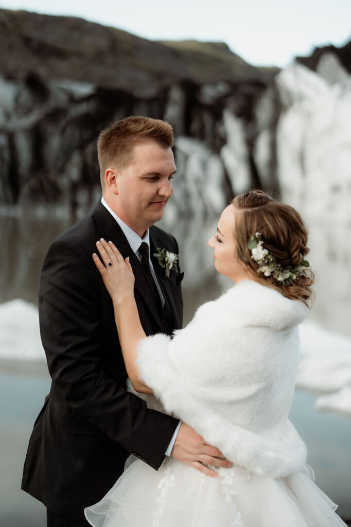 bride and groom stand below clacier during dreamy iceland elopement.