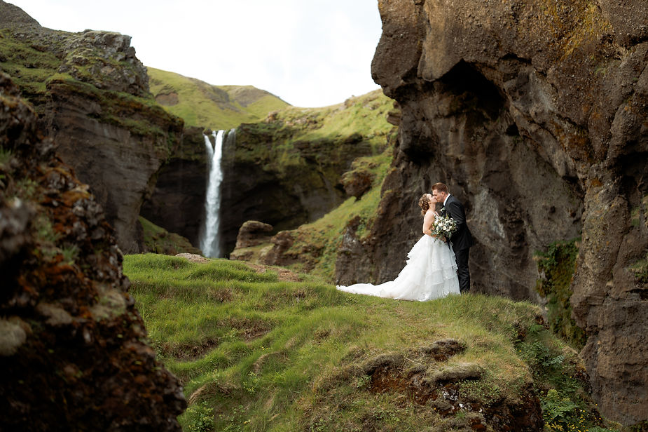 bride and groom kiss in valley by waterfall during iceland adventure elopement.