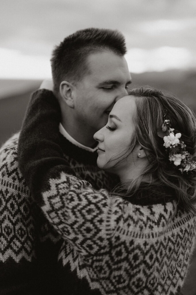 black and white photo of a bride and groom embracing, him kissing her head during iceland wedding portraits.