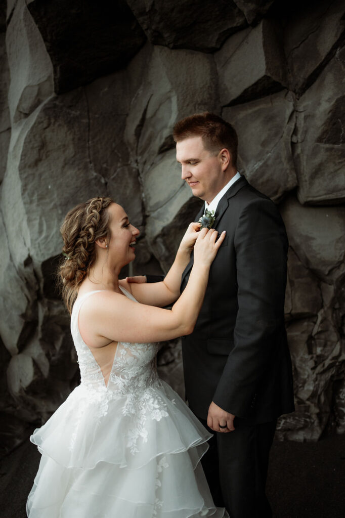 bride fixes groom's flowers, during dreamy iceland wedding.