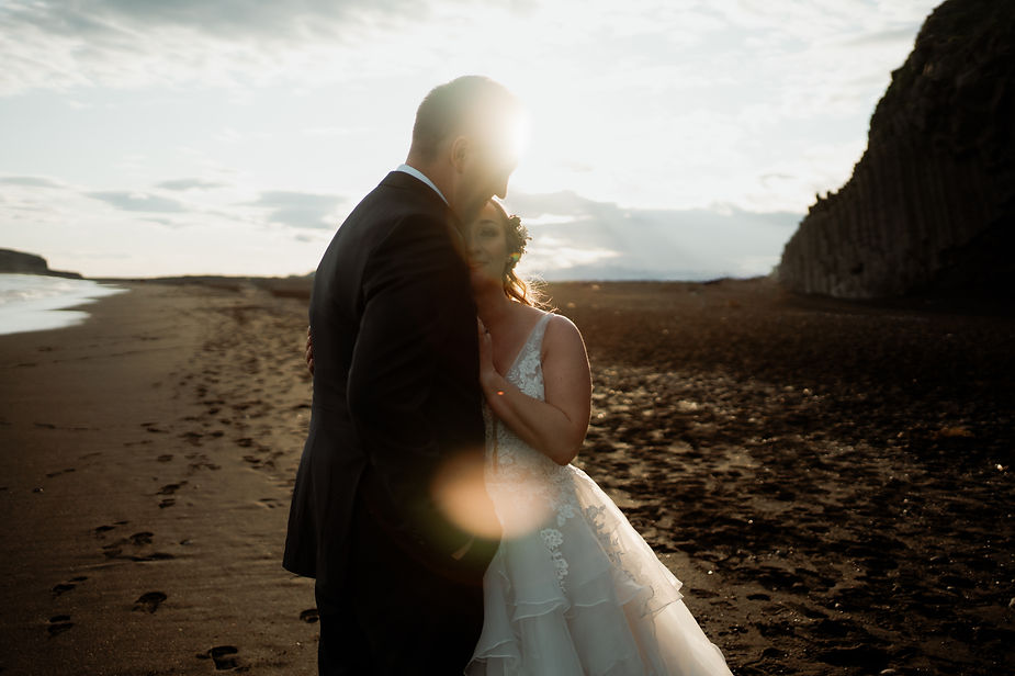 bride and groom hug on iceland coast during adventure elopement wedding.