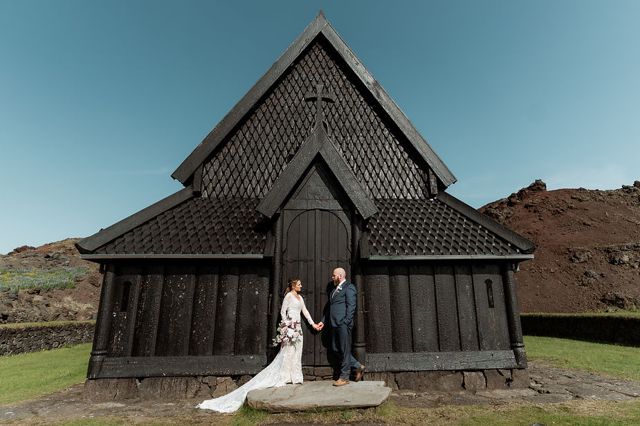 bride and groom stand in front of black church during iceland wedding photos.