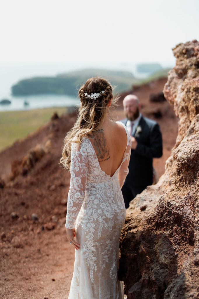 bride and groom stand by vibrant red rocks during iceland wedding photo shoot.