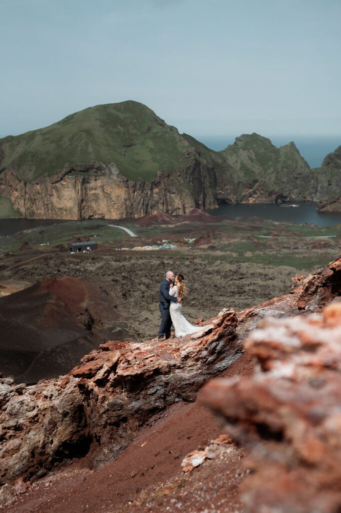 bride and groom kiss on rocky overlook during iceland wedding photo shoot with elopement photographer.