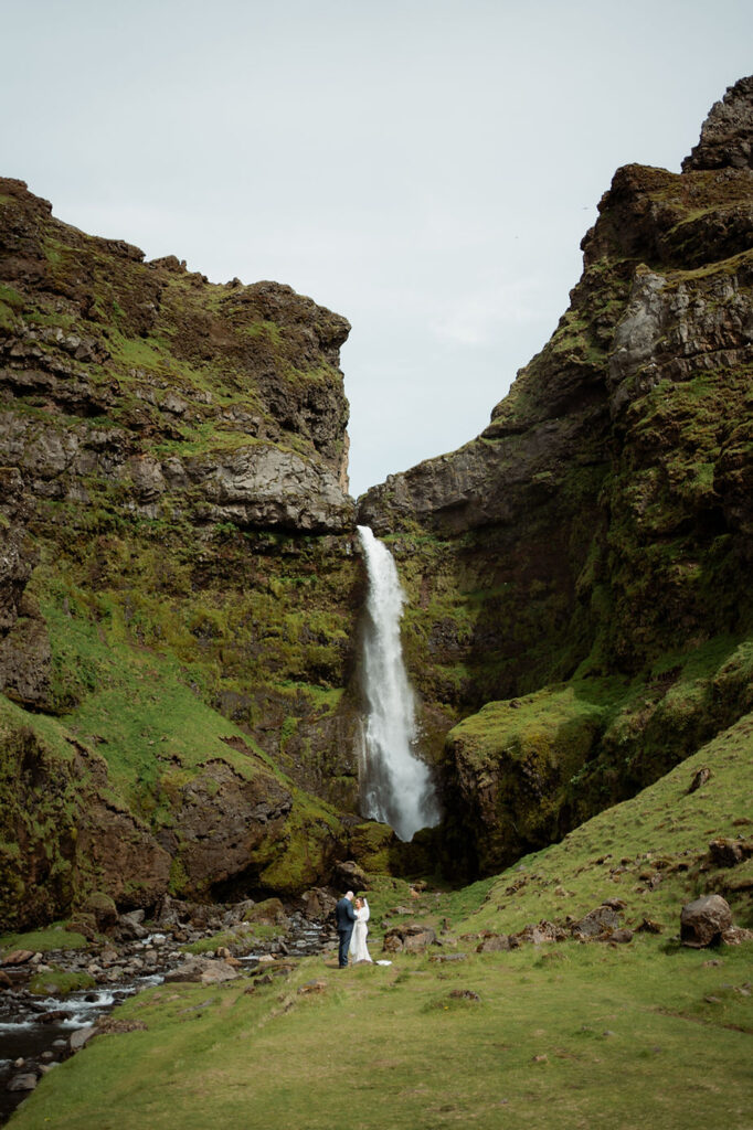 Bride and groom at the bottom of a waterfall during iceland adventure wedding in the westman islands.