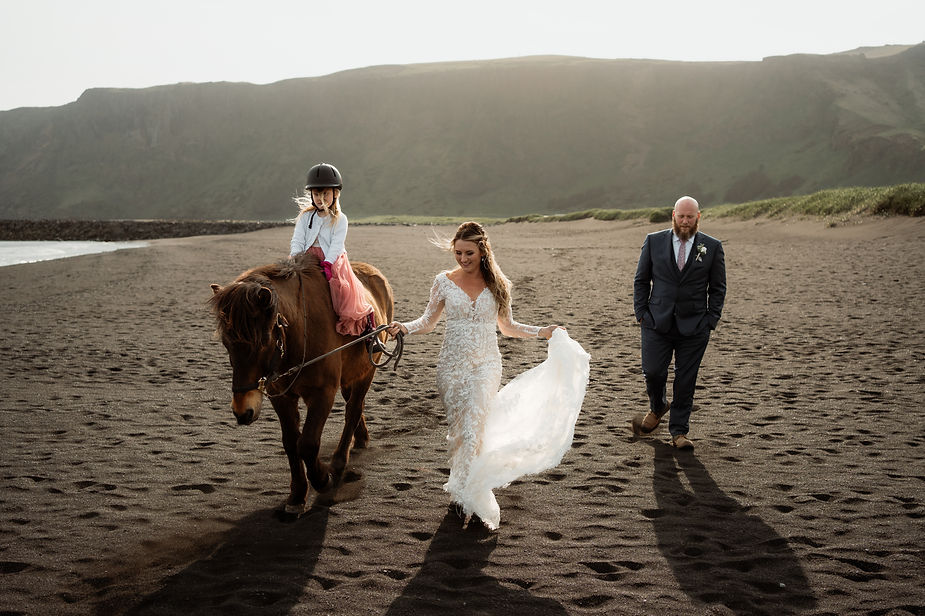 bride, groom, and daughter ride horses on the beach during iceland adventure wedding with elopement photographer