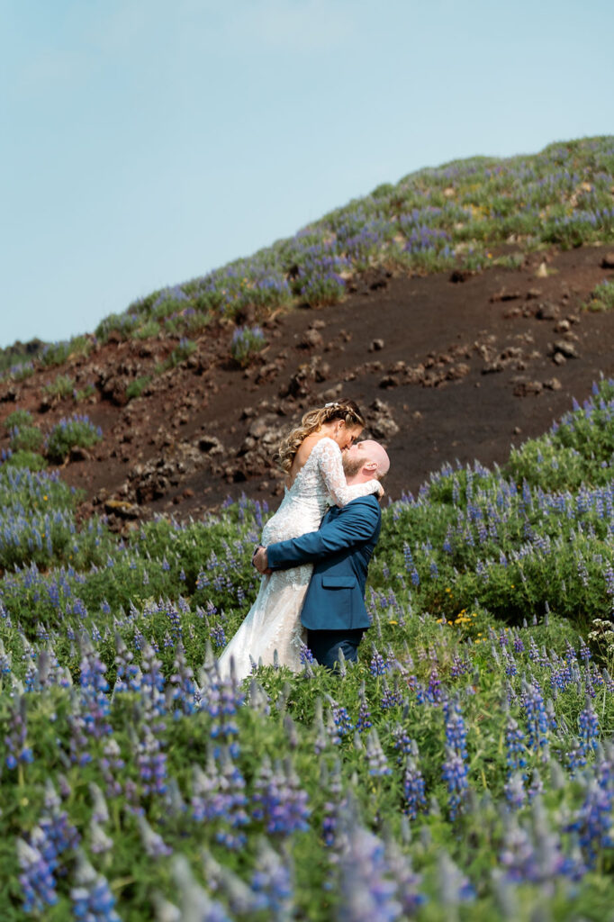 bride and groom kiss in field of lupin flowers during iceland wedding photo shoot.