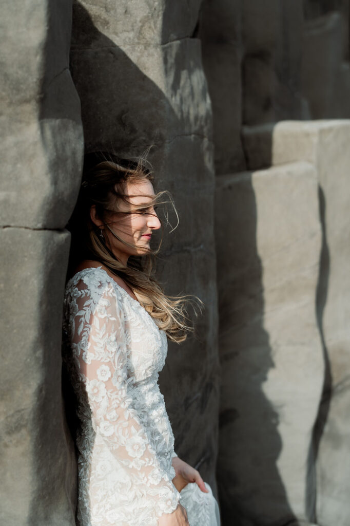 bride stands against rock during iceland wedding photos.