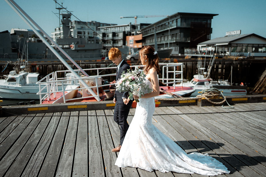 two brides walk down the harbor in reykjavik during their iceland wedding.