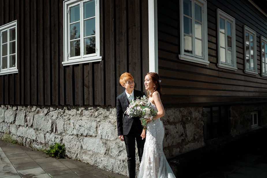 lgbtqi+ couple stands on the side of a building during their downtown reykjavik wedding photos.