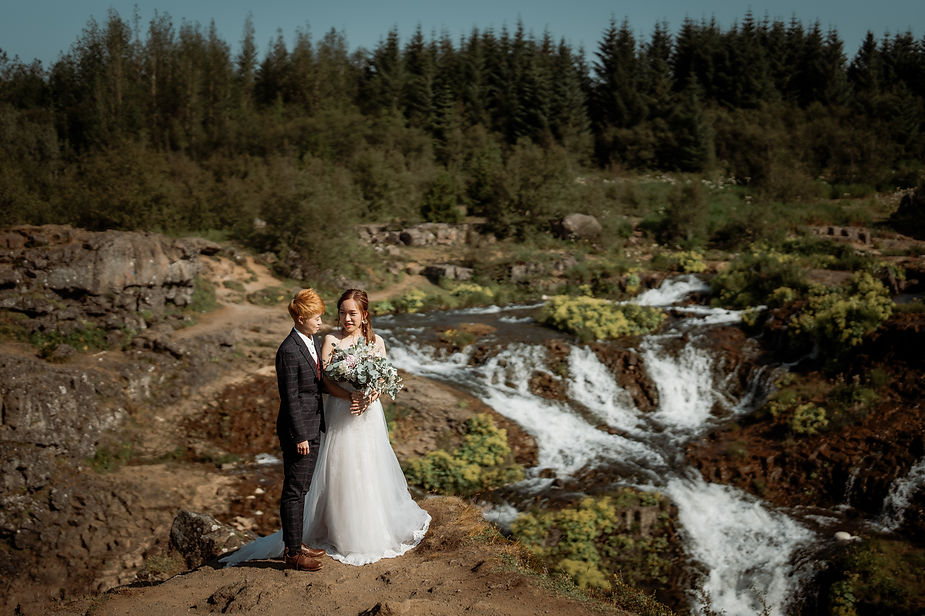 lgbtqi+ couple stands on grassy edge during their iceland wedding in reykjavik.