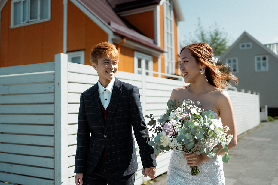 lgbtqi+ couple walks hand in hand down the streets of reykjavik during their iceland wedding photos.