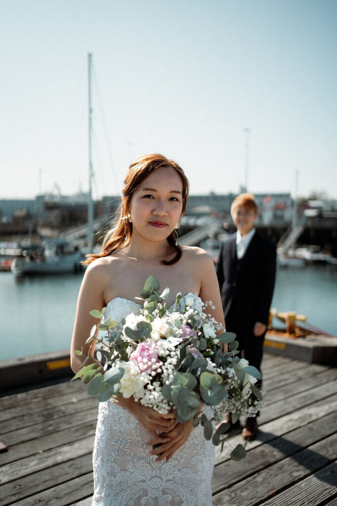 lgbtqi+ couple stands and smiles on reykjavik harbour during iceland wedding photos.