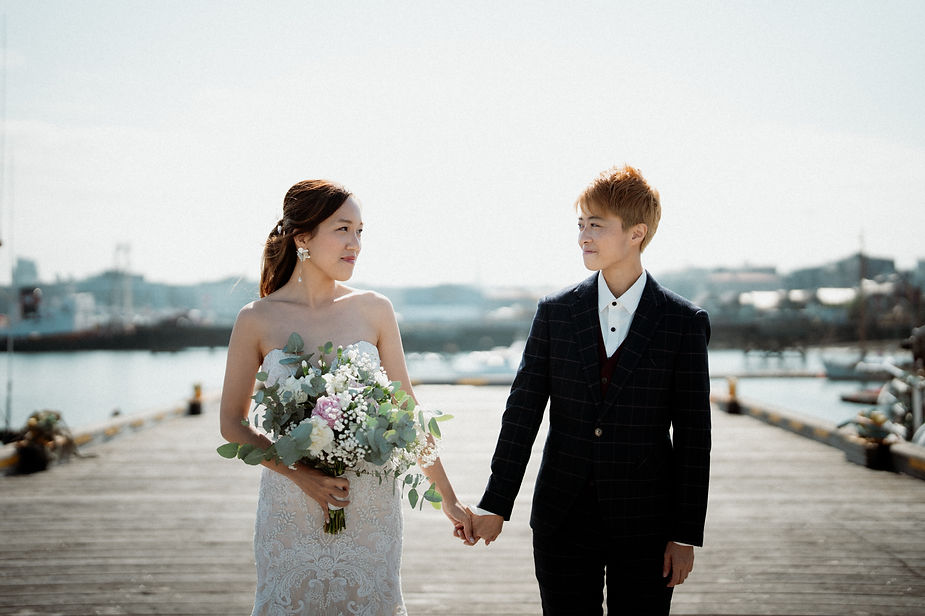 lgbtqi+ partners hold hands and look at each other on reykjavik harbour during destination elopement in iceland.