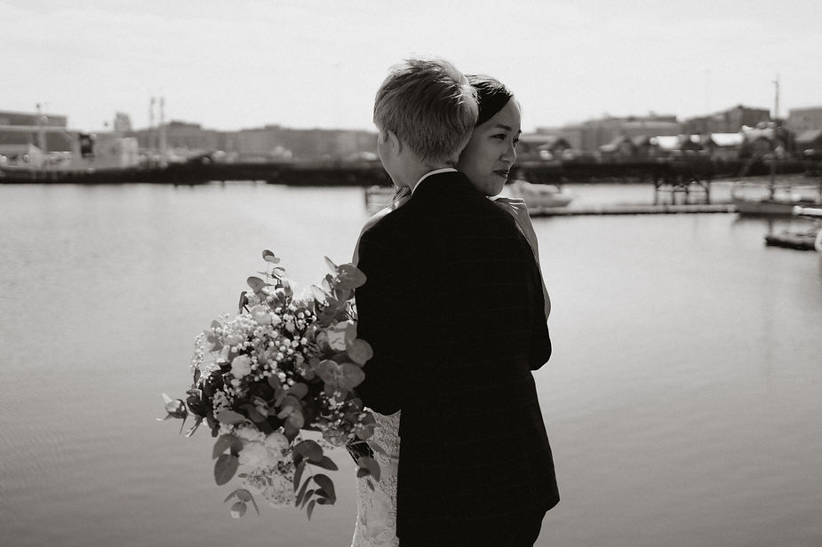 lgbtqi+ couple hugs on reykjavik harbour during destination wedding photos in iceland.