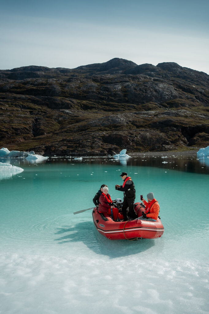 people in a small boat on the coast of greenland during destination elopement wedding.