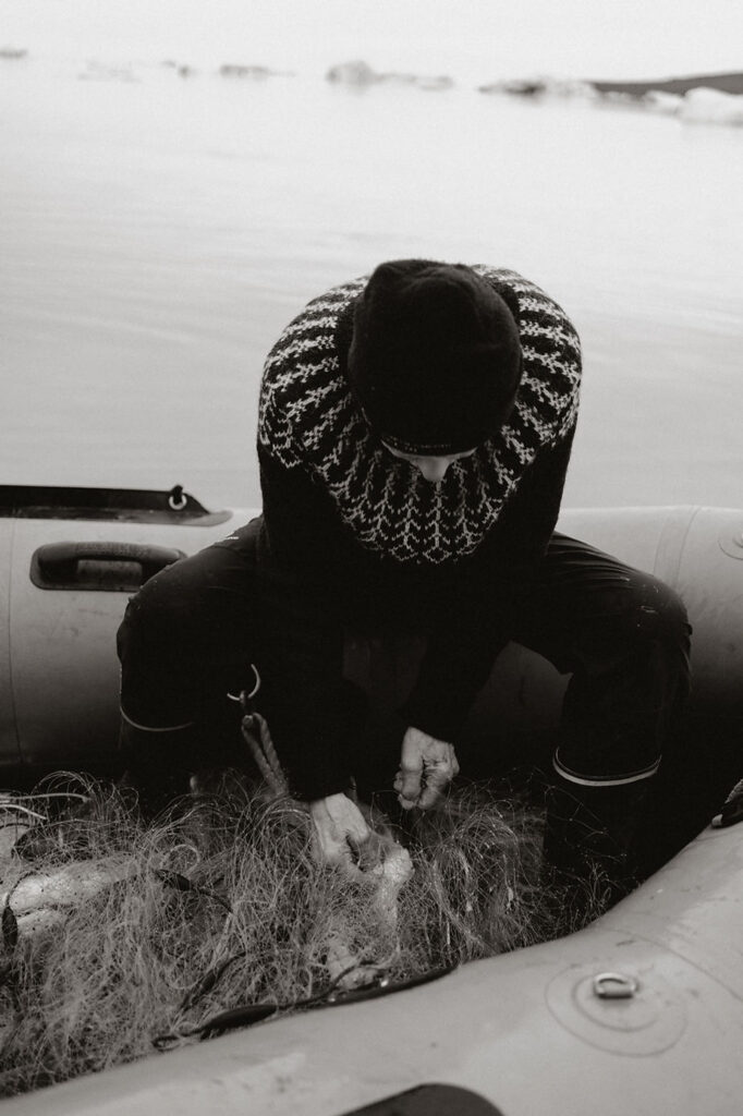 person takes fish out of net during adventure elopement in greenland.