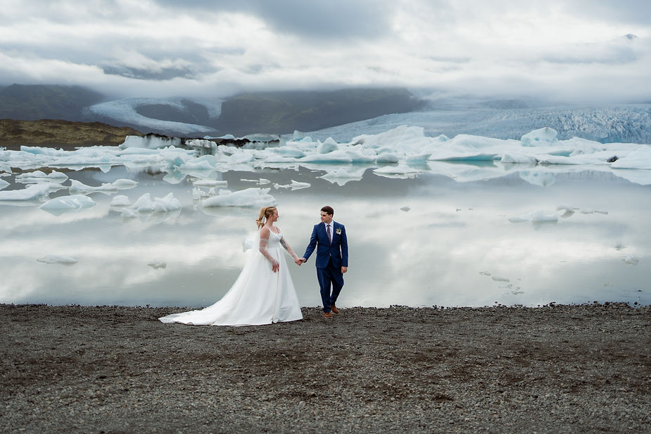 bride and groom walk along coast during iceland wedding day.