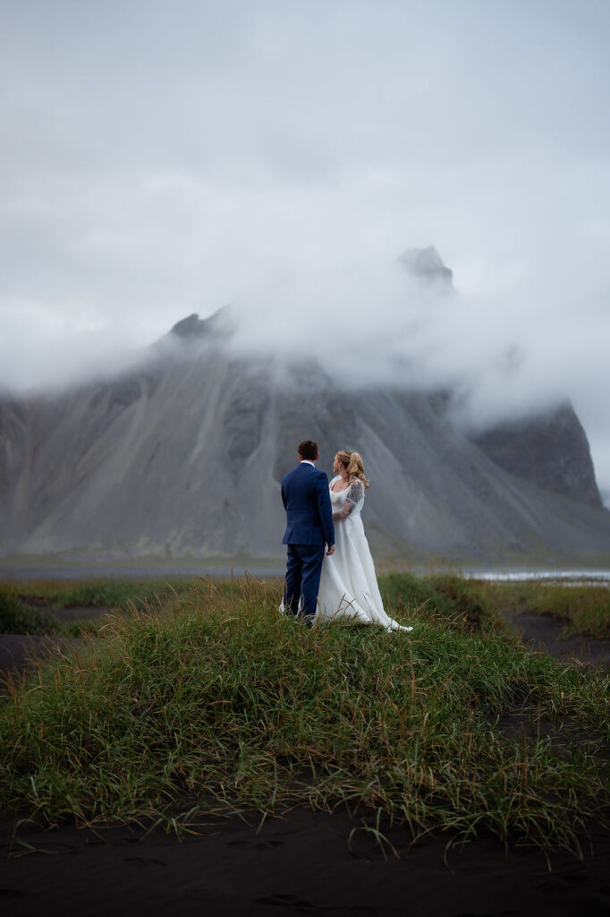 bride and groom stand at base of mountain during iceland wedding adventure.