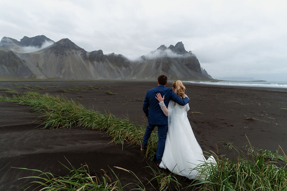 bride and groom stand on black sand beach for their iceland wedding day.