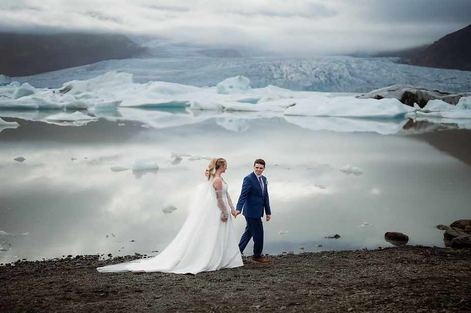 bride and groom walk in front of glacier during adventure elopement with iceland wedding photographer.