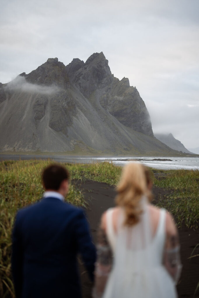 bride and groom stand at base of mountain with iceland wedding photographer during adventure wedding.