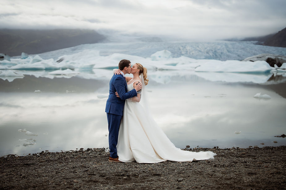 bride and groom kiss in front of glacier during adventure wedding in iceland with photographer.