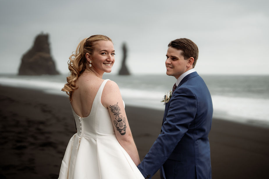 groom looks at bride and smiles as bride looks at iceland wedding photographer.