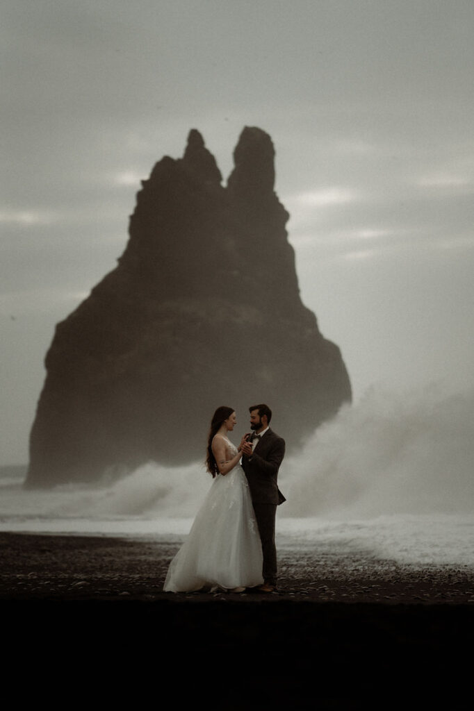 bride and groom stand on beach in iceland during photo shoot.