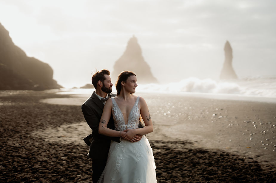 bride and groom embrace on a beach in reynisfjara iceland.