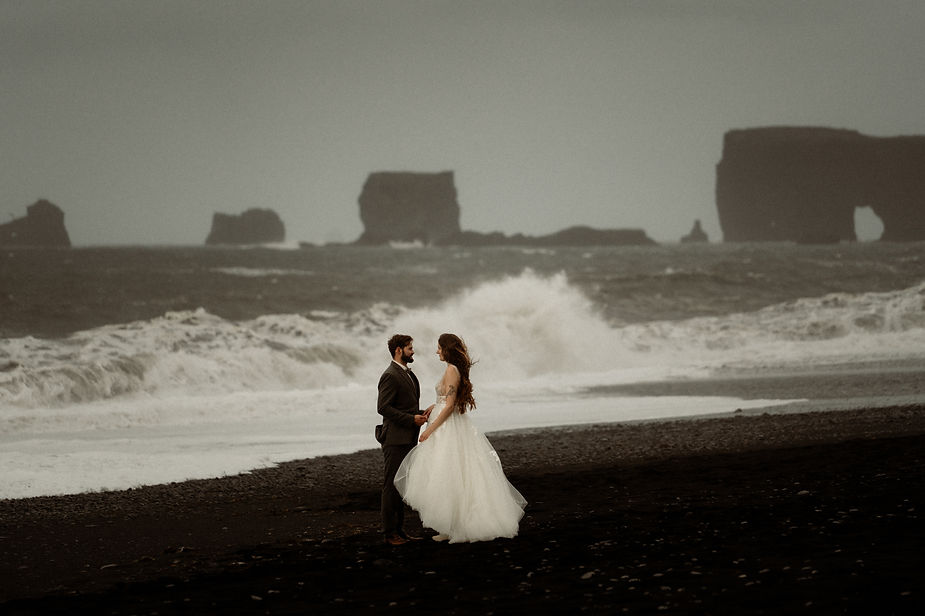 bride and groom stand on black sand beach during honeymoon with iceland wedding photographer.