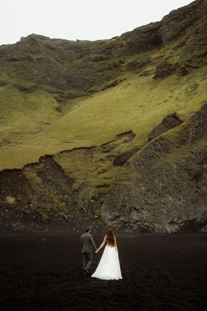 bride and groom pose on black sand beach for iceland wedding photographer.