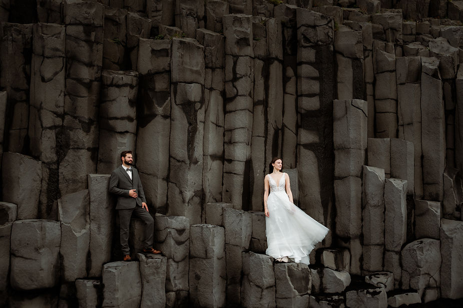 bride and groom stand on rock formations during iceland honeymoon photo shoot.