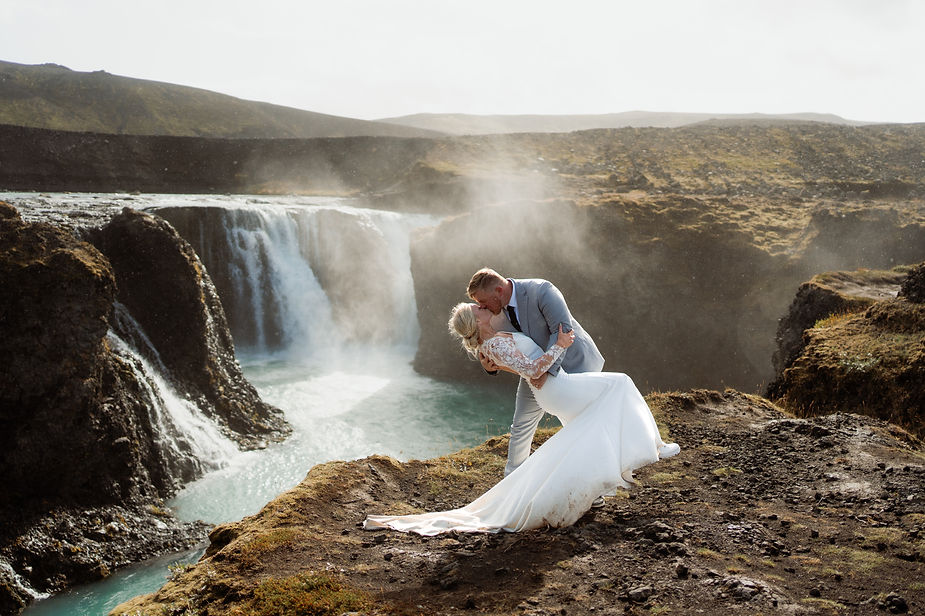 bride and groom kiss in front of waterfall during iceland elopement.
