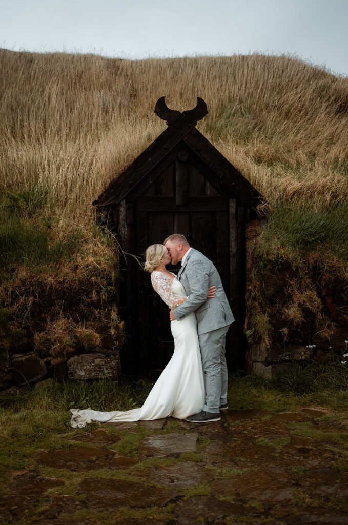bride and groom kiss in front of small shelter during iceland wedding photos.