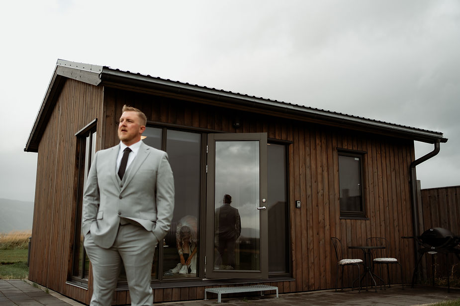 Groom waits outside cottage for bride.