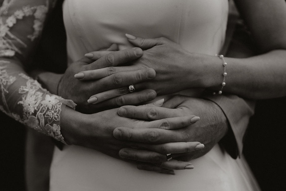 close up image of bride and grooms hands and wedding rings.