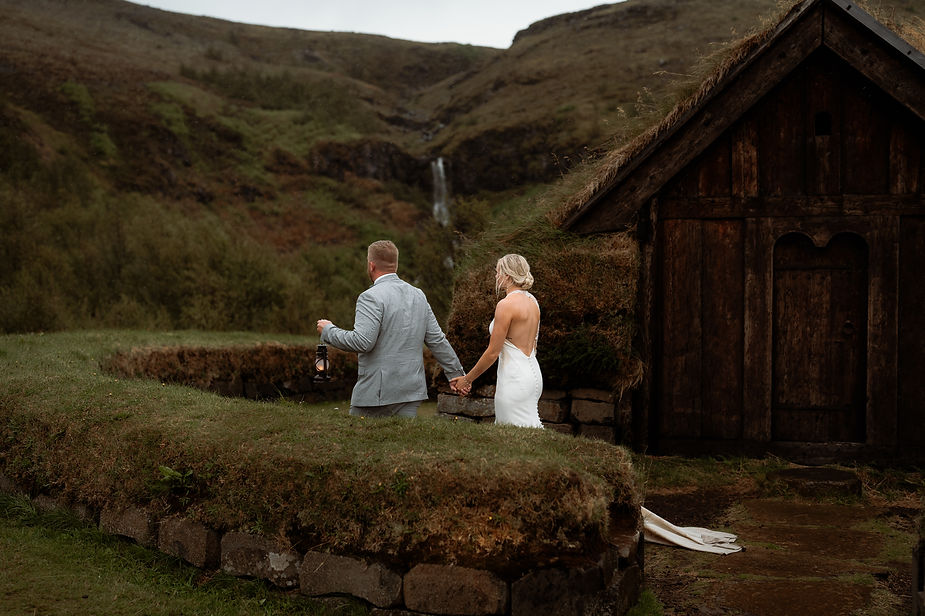 bride and groom walk around small grassy building in iceland during elopement day.