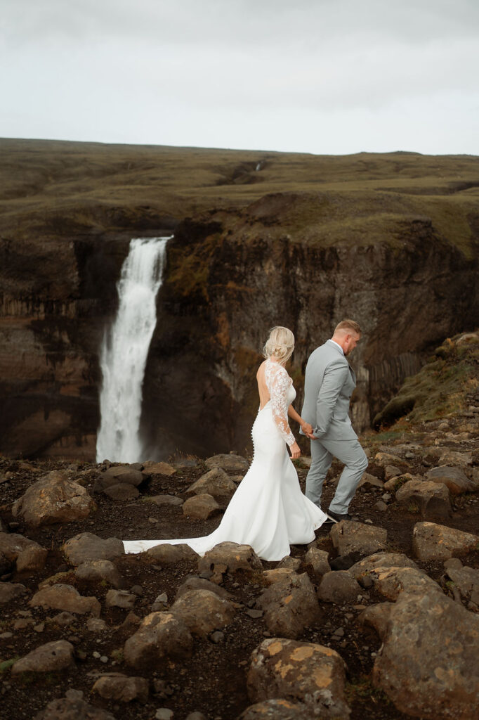 bride and groom hike around valley during iceland wedding day adventure.