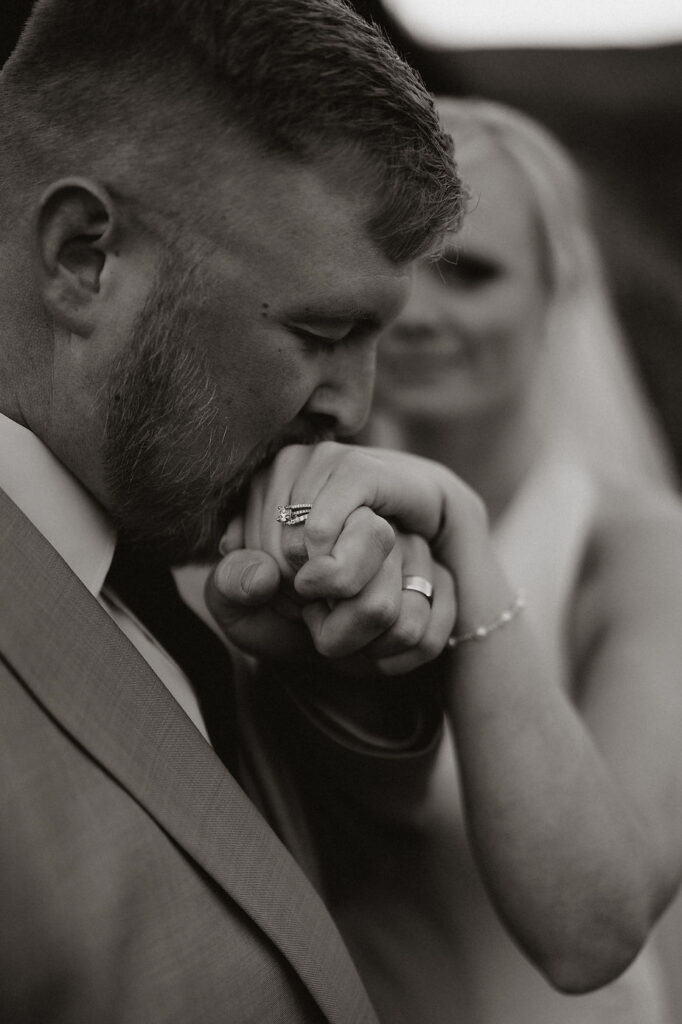 groom kisses brides hand and wedding ring.
