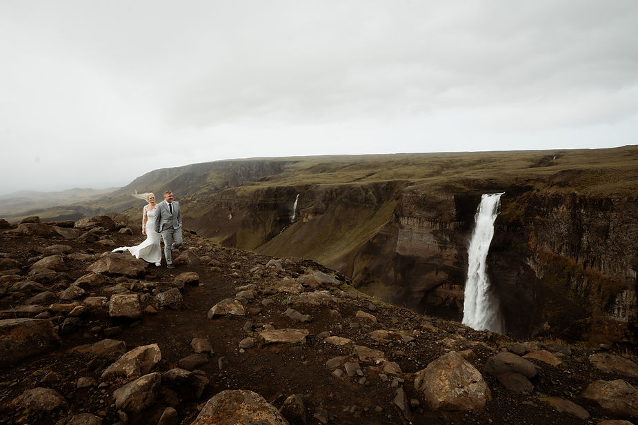 bride and groom walk along valley edge during iceland wedding photos.