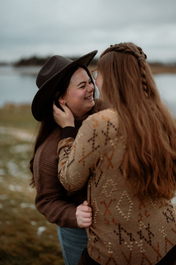 lgbtq+ couple smile and go in for a kiss during iceland proposal photos.