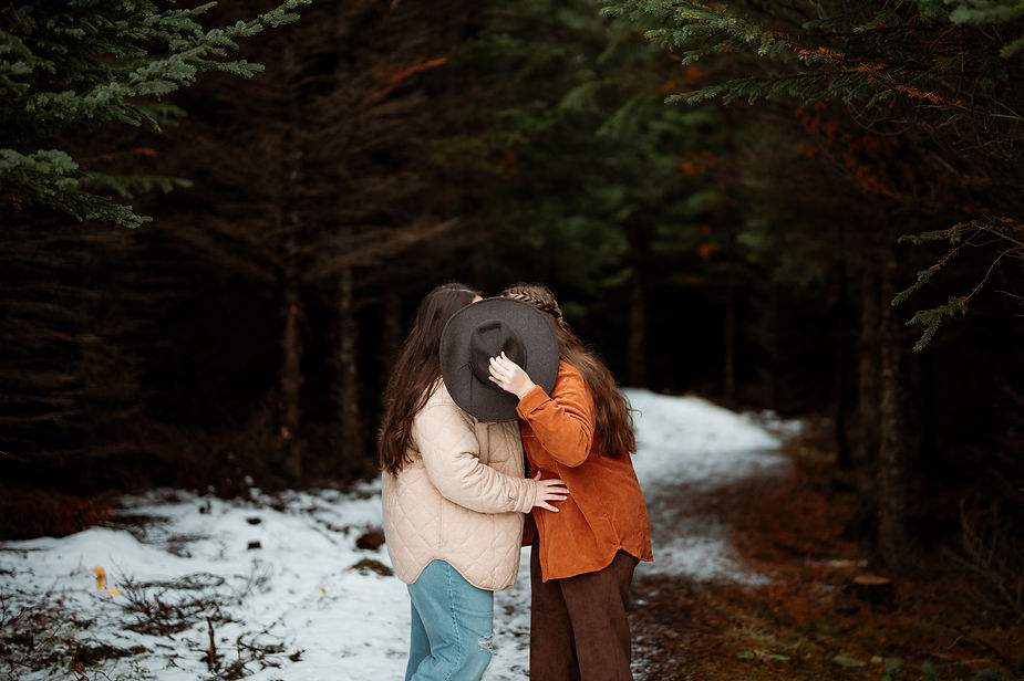 lgbtq+ couple kiss behind a hat during engagement photo shoot with iceland photographer.
