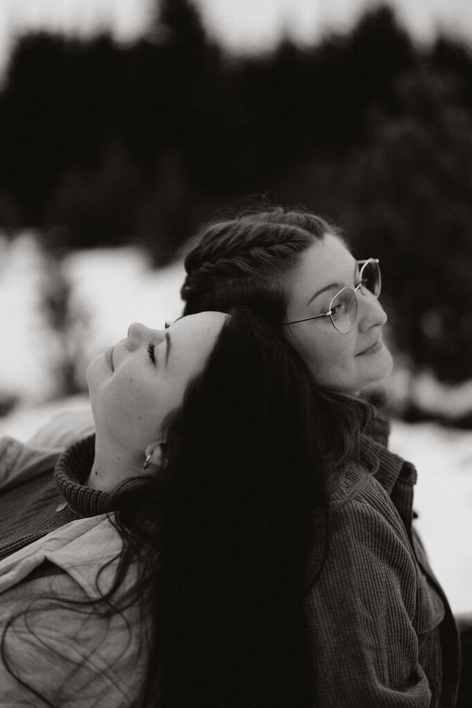 lgbtq+ couple lean on each others backs and smile during iceland engagement pictures.